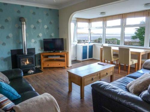 a living room with a couch and a table with a fireplace at Oyster Catcher in Mainsriddle