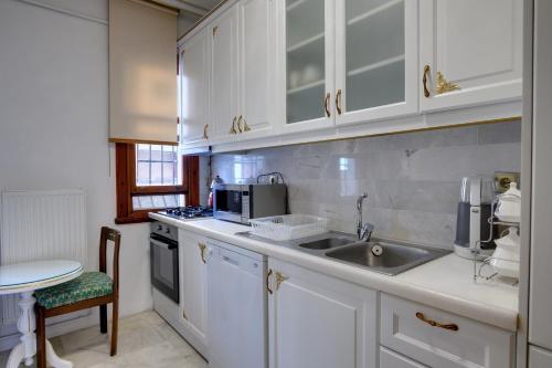 a kitchen with white cabinets and a sink at Emirganlı Ottoman House in Istanbul