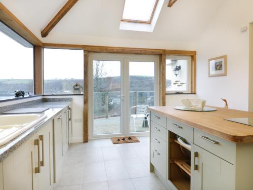 a kitchen with white cabinets and a large window at Treetops in Fowey