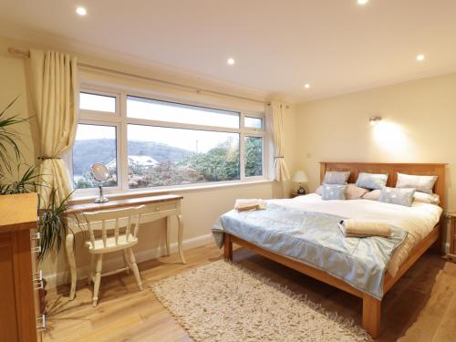 a bedroom with a bed and a desk and a window at Treetops in Fowey