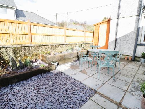 a patio with a table and chairs and a fence at Llwyn Onn in Dolwyddelan