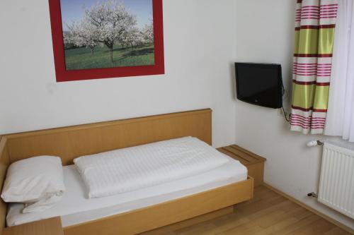 a small bedroom with a bed and a tv at Gasthof Pension Zum goldenen Hirschen in Burgbernheim