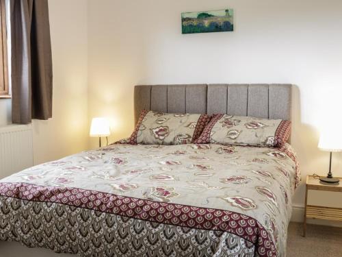 a bed in a bedroom with two lamps and a bedspread at Acorn Cottage 2 in Petton