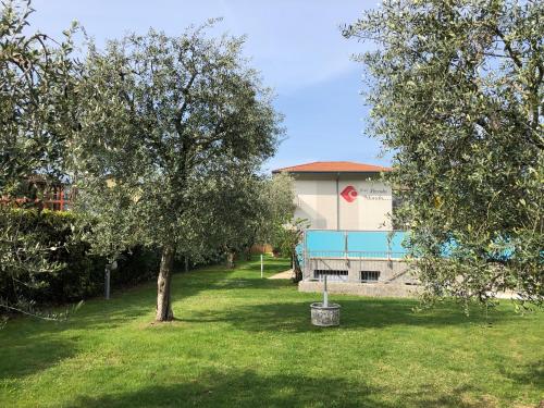 a building with a tree in the grass at Hotel Piccolo Mondo in Nago-Torbole