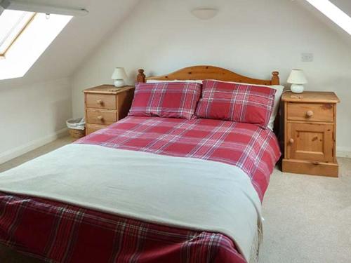 - un lit rouge et blanc dans une chambre avec 2 tables de chevet dans l'établissement Creag Mhor Cottage, à Dornie