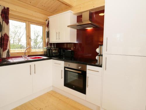 a kitchen with white cabinets and black counter tops at The Shippen in West Chinnock