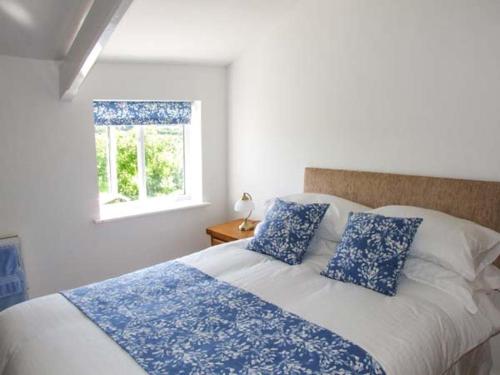 a bedroom with a bed with blue pillows and a window at Cotswold View in Shottery