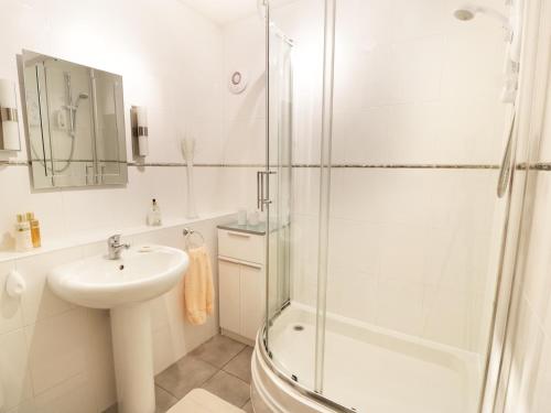 a white bathroom with a sink and a shower at MACS Place in Largs