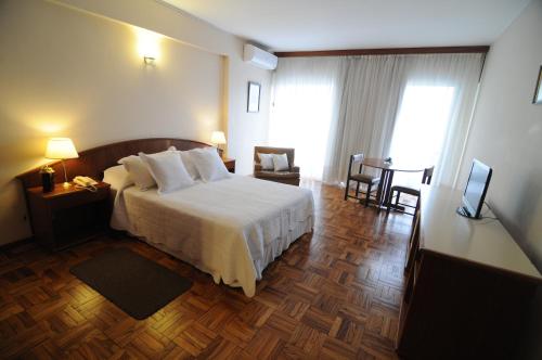 a hotel room with a bed and a table at Hotel Los Cedros in Salto