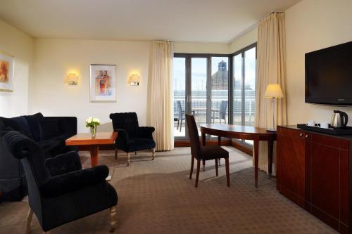 a living room with a table and chairs and a television at Sheraton Carlton Nuernberg in Nuremberg
