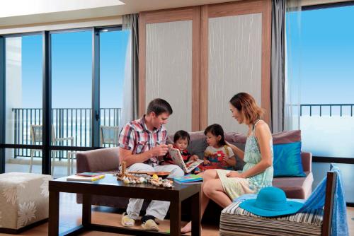 a family sitting on a couch in a living room at Moon Ocean Ginowan Hotel & Residence in Ginowan