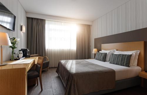 Habitación de hotel con cama y escritorio en Mercure Lisboa Almada en Almada