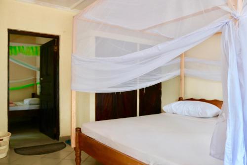 ein Schlafzimmer mit einem weißen Bett mit Baldachin in der Unterkunft A wonderful Beach property in Diani Beach Kenyaa dream holiday place in Mombasa