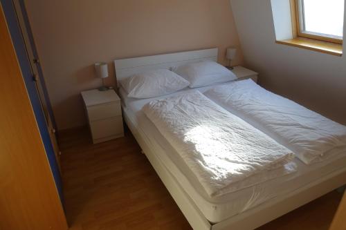 a bed with white sheets and pillows in a bedroom at Apartments Kaninska Vas in Bovec