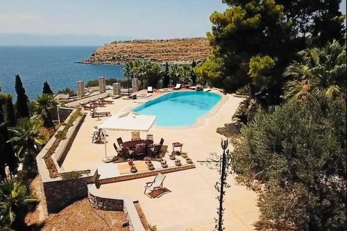 a swimming pool with chairs and the ocean in the background at Pyrgi Spetses in Spetses