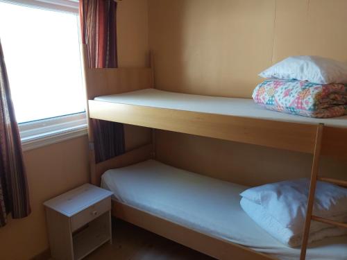 オップダールにあるMagalaupe Campingの二段ベッド2台、窓が備わる小さな客室です。