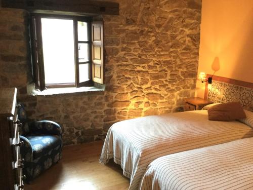a bedroom with a bed and a stone wall at Olmares Terrace Apartment - Picos de Europa in Lomeña