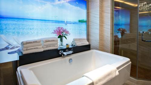 a bathroom with a bath tub with a picture of the ocean at Nanjing Central Hotel in Nanjing