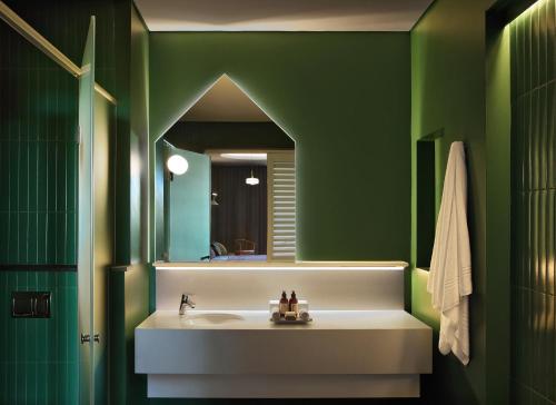 a green bathroom with a sink and a mirror at Home Suite Hotels Rosebank in Johannesburg