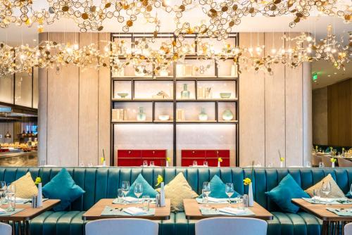 a dining room with tables and chairs and chandeliers at Conrad Shanghai in Shanghai