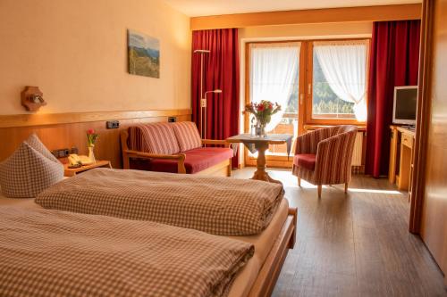 a hotel room with two beds and a television at Berg- und Aktivhotel Edelsberg GmbH in Bad Hindelang
