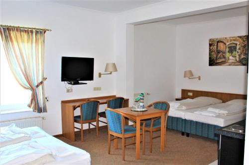 ヘンシュテット・ウルツブルクにあるHotel Alsterquelleのベッド2台、テーブルと椅子が備わるホテルルームです。