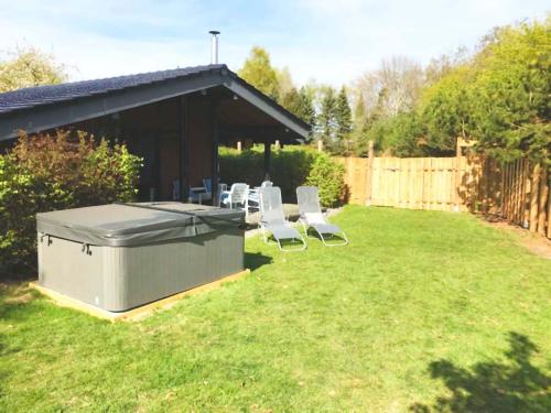 a backyard with a barbecue grill and chairs in the grass at Wellness Chalet No10 in Kellenhusen
