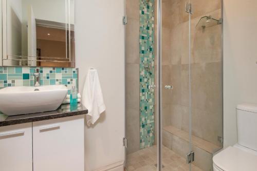 ein Bad mit einem Waschbecken und einer Dusche in der Unterkunft Walker Bay Luxury Seafront Apartment in Hermanus