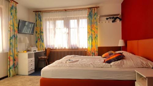 ローテンブルク・オプ・デア・タウバーにあるブティックホテル ゴールデネ ローズの赤い壁のベッドルーム1室(ベッド1台付)