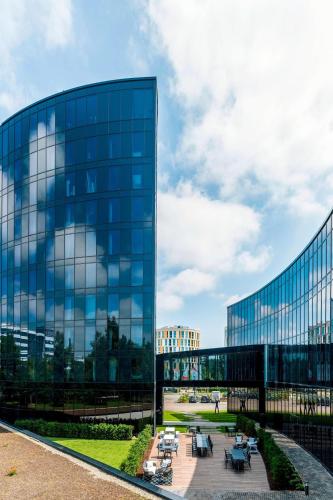 a glass building with tables in front of it at Airport Plaza Hotel Hamburg in Norderstedt