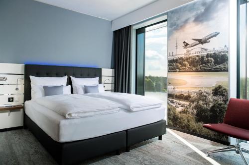 a bedroom with a bed and a large window at Airport Plaza Hotel Hamburg in Norderstedt