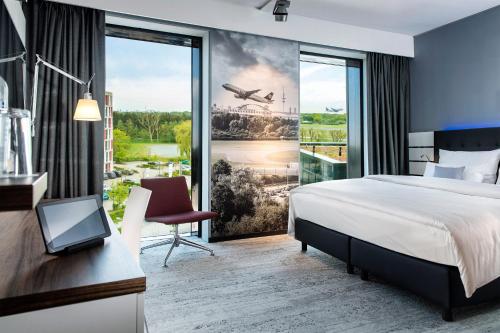 ノルダーシュテットにあるAirport Plaza Hotel Hamburgのベッドと大きな窓があるホテルの部屋
