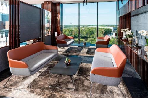 a lobby with couches and tables and windows at Airport Plaza Hotel Hamburg, vorher bekannt als Nordport Plaza Hotel in Norderstedt
