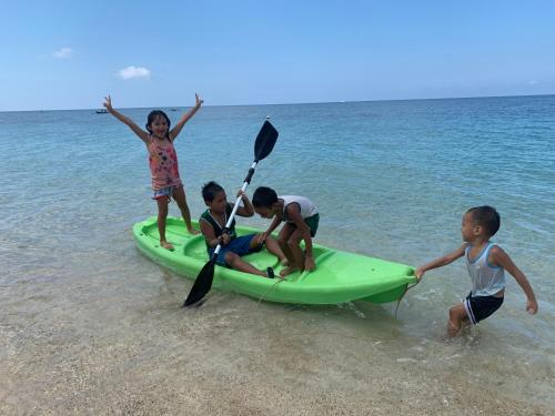 three children playing on a paddle board on the beach at The Beach House Carabao Island in San Jose