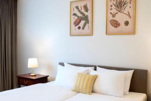 a bedroom with a white bed with two pictures on the wall at Klub Sosnowy in Warsaw