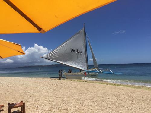 a small sail boat on the beach with people on it at The Beach House Carabao Island in San Jose