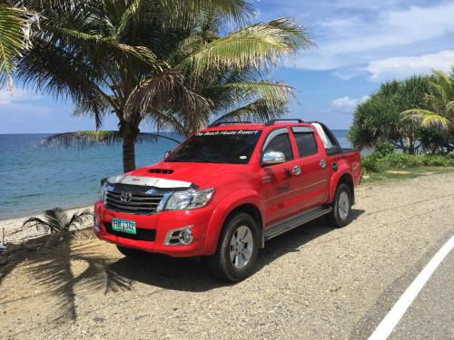 a red truck parked on a road near the beach at The Beach House Carabao Island in San Jose