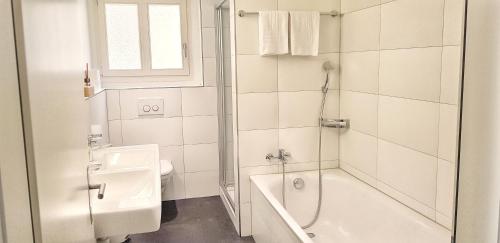 un bagno bianco con vasca e lavandino di Easy-Living Apartments Lindenstrasse 21 a Lucerna
