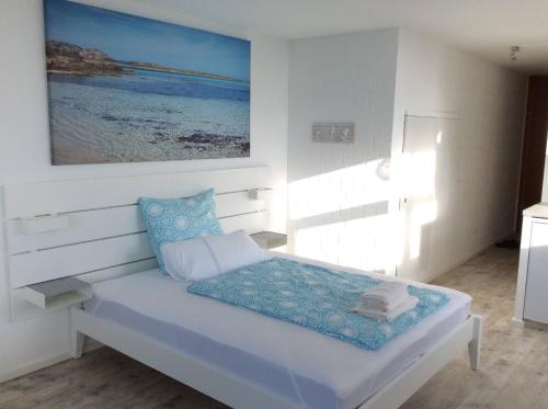 a white room with a bed with a painting on the wall at Wellness Apartment Sankt Englmar in Sankt Englmar