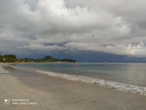 a beach with a cloudy sky and the ocean at Bungalows des tropiques in Nosy Be