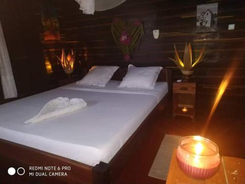 a couple of beds in a room with a candle at Bungalows des tropiques in Nosy Be