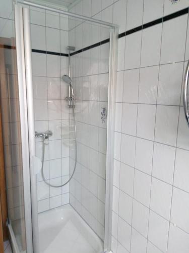 a white tiled shower with a glass door at Ferienwohnung Frieda in Nüdlingen