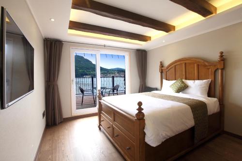 a bedroom with a bed and a large window at Tongyeong Hansan Marina Resort in Tongyeong