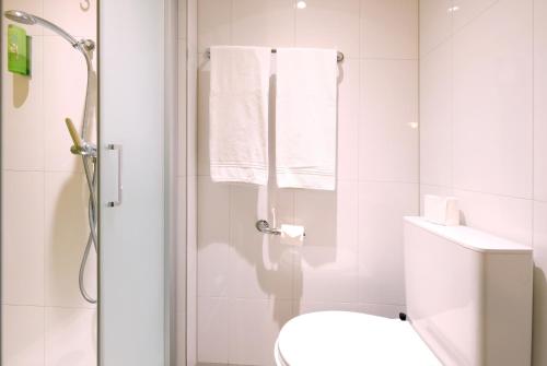 a bathroom with a toilet and a shower with towels at Barabas Luzern in Luzern