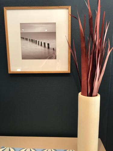 a white vase with a plant in it next to a mirror at Taras Rom og leiligheter in Kragerø