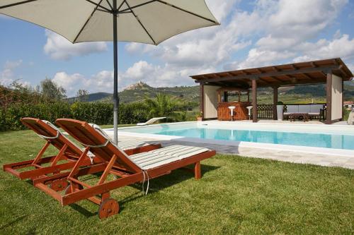 a pair of chairs and an umbrella next to a swimming pool at Holiday home with exclusive swimming pool in the Tuscan Maremma in Montemassi