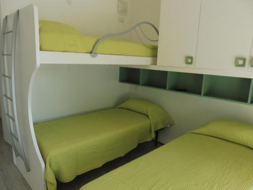 two beds in a small room with green sheets at Residence Caorle App. n. 5 in Caorle