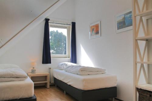een slaapkamer met 2 bedden en een raam bij Kruisweg 4 in Callantsoog