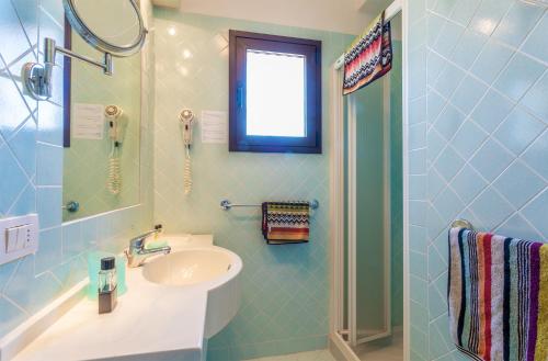 uma casa de banho em azulejos azuis com um lavatório e um chuveiro em Centro Vacanze Isuledda em Cannigione