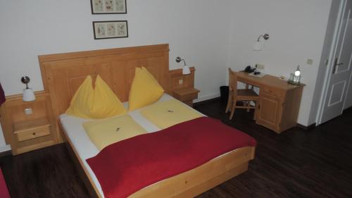 a bedroom with a bed with yellow pillows and a desk at Frühstückspension Barbara in Pöchlarn